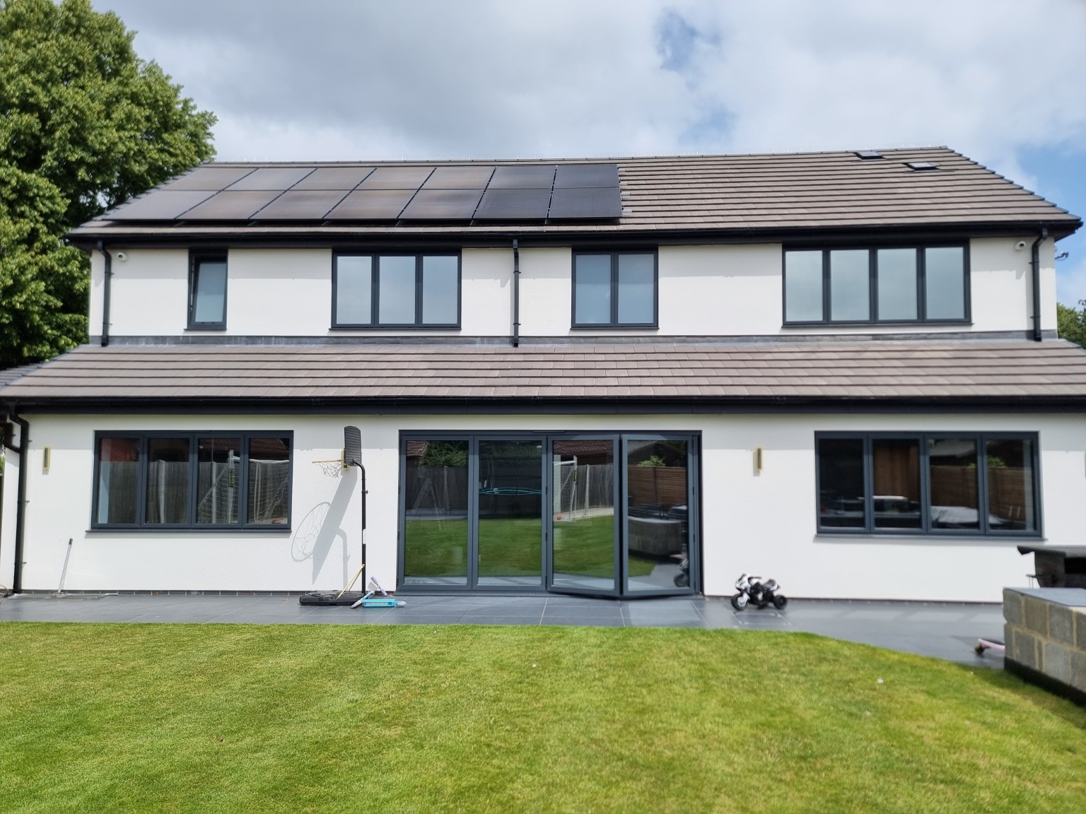 Modern two-storey home with large dark-framed windows overlooking a garden